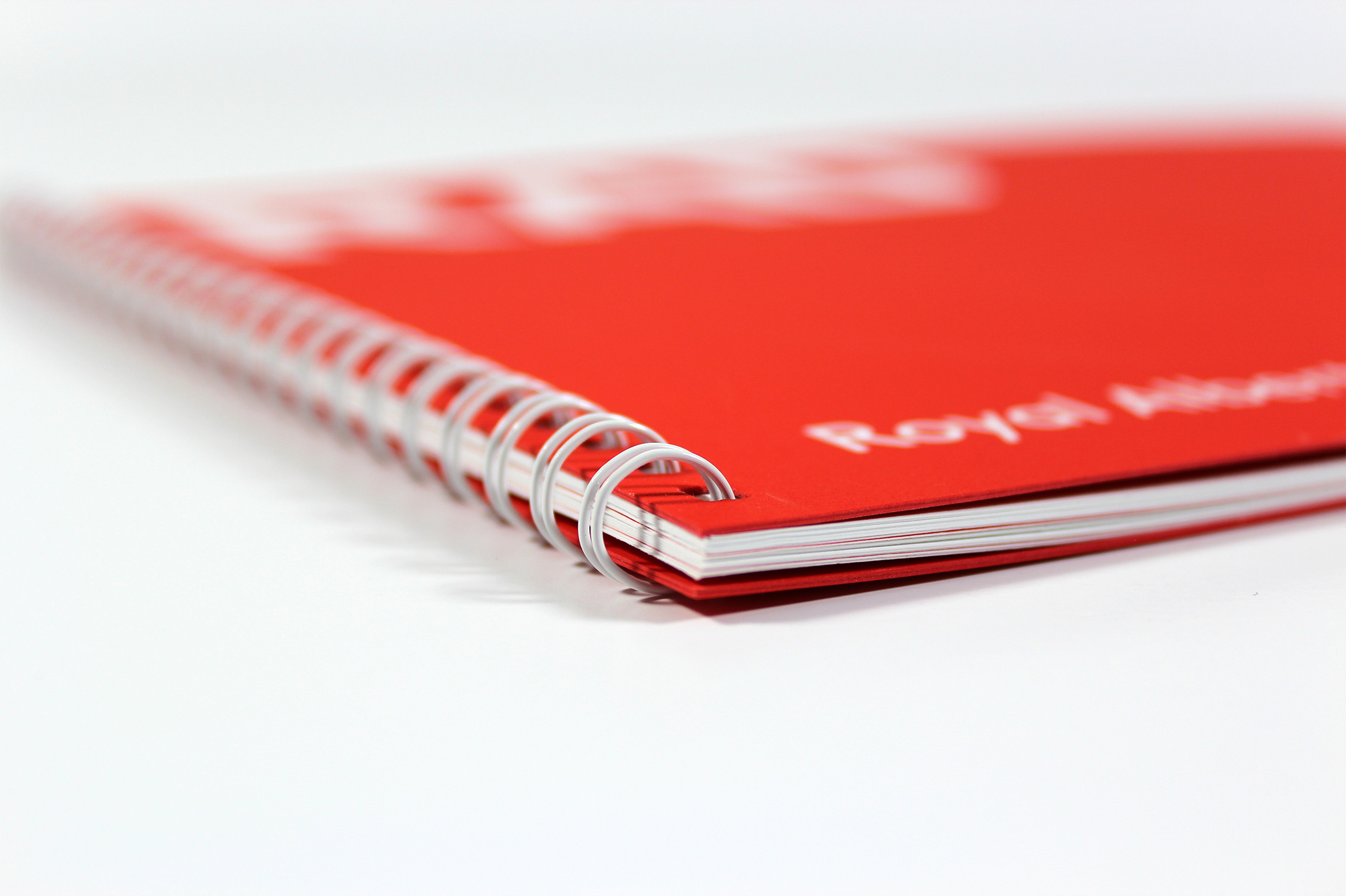 Printed Wiro-bound corporate promotional brochure for RAD - close-up showing the binding and red card front cover